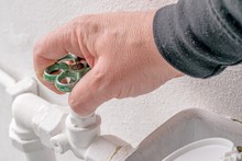A Hand Turning The Stopcock Valve Of A Water Heating System