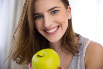 Canvas Print - Closeup portrait of a smiling young woman with green apple