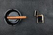 Lighter and black ashtray with cigar