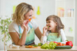 © Oksana Kuzmina - kid girl and mother eating healthy food vegetables