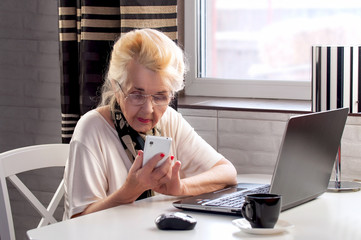 elderly lady talking on the phone and woking with computer