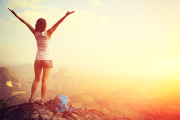 strong confident woman hiker open arms at on mountain peak rock
