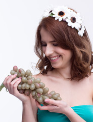 Canvas Print - Young smiling woman holding bunch of grapesand looking on it