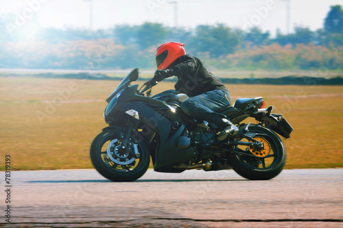 Naklejka na szybę young man riding motorcycle in asphalt road curve with with a mo