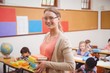© WavebreakMediaMicro - Teacher smiling at camera while holding stack of notebooks