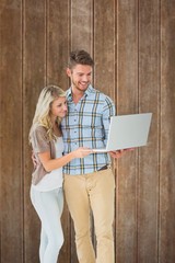 Poster - Composite image of attractive couple standing and using laptop