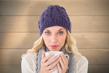 Poster - Composite image of pretty blonde in winter fashion holding mug
