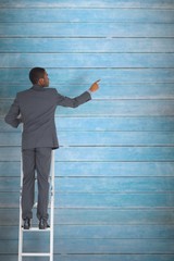 Poster - Composite image of businessman standing on ladder pointing