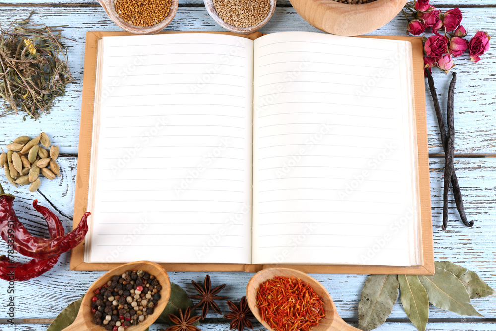 Spices with recipe book on color wooden table background