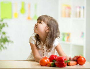 Wall Mural - kid girl with expression of disgust against vegetables