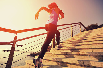 Poster - young fitness woman running on seaside stone stairs