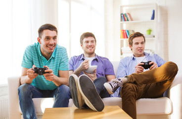 Wall Mural - smiling friends playing video games at home