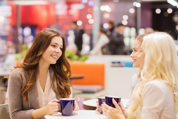 Canvas Print - smiling young women drinking coffee in mall