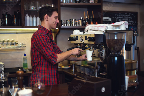 Fotografie, Obraz Young handsome barista hipster making coffee for his clients in