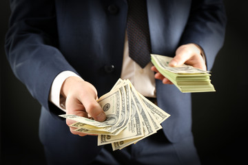 Businessman giving money on dark background