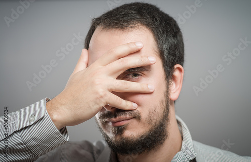 Fotografie, Obraz Portrait of a handsome man covering his eyes with hand