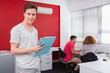 © WavebreakmediaMicro - Smiling student holding notebook and phone near classmates