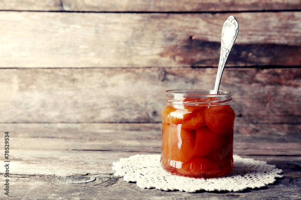 Jar of tasty jam on wooden background