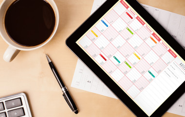 Wall Mural - tablet pc showing calendar on screen with a cup of coffee on a d