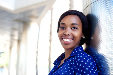 Smiling young woman in blue shirt standing outdoors