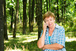 © kostyha - Old woman talking on the phone in the forest