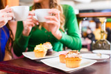 Frauen essen Muffins beim Kaffee trinken