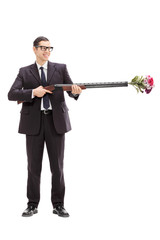 Wall Mural - Businessman holding a rifle loaded with flowers