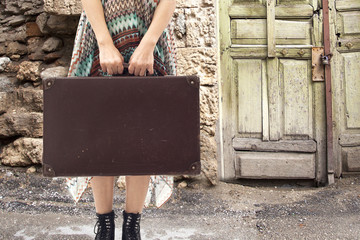 Young woman standing with suitcase on road