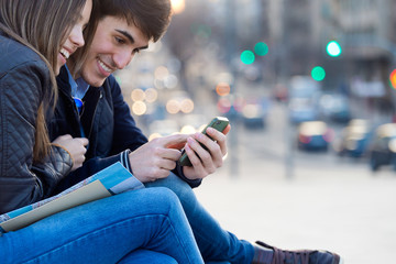 Young couple of tourist in town using mobile phone.