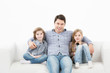 © BestForYou - Family sitting on sofa smiling at camera on white background