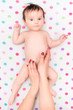 Little baby girl lying on blanket with colourful polka dots