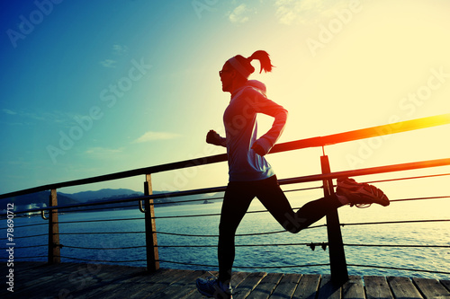 Cuadros en Lienzo young fitness woman running on seaside boardwalk