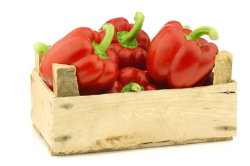 red bell peppers (capsicum) in a wooden crate on a white backgro