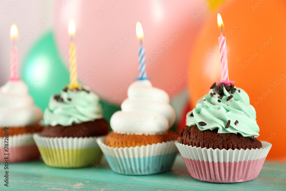 Delicious birthday cupcakes on table on bright background