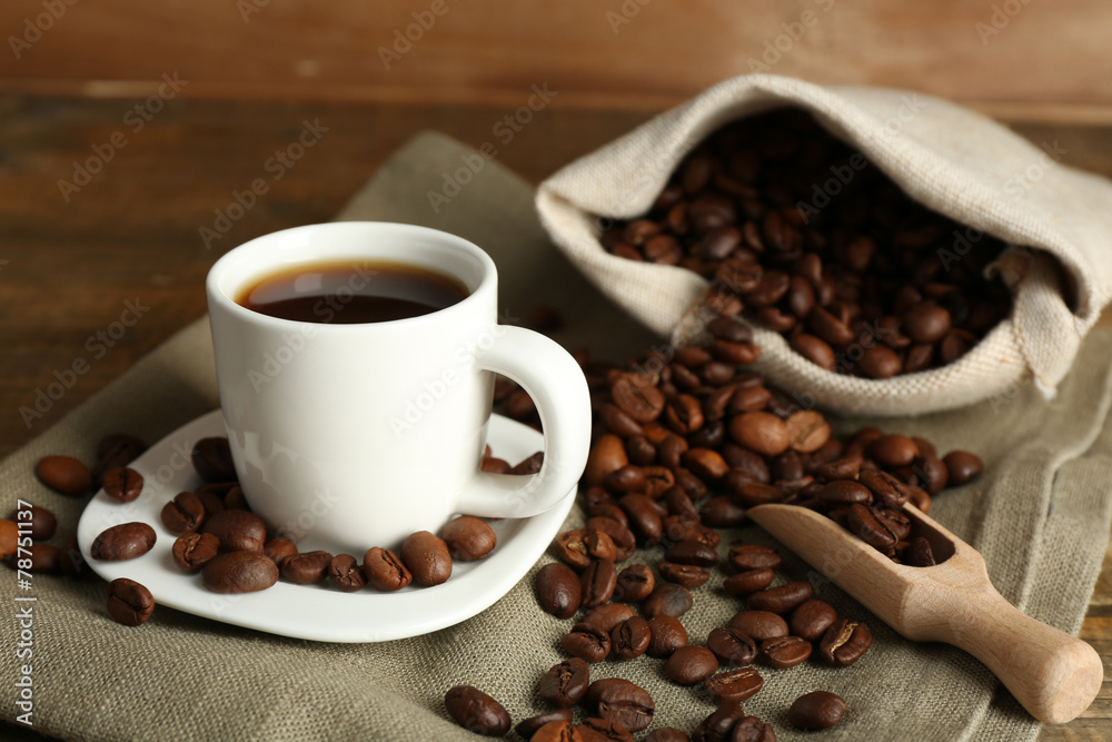 Cup of coffee with beans on rustic wooden background