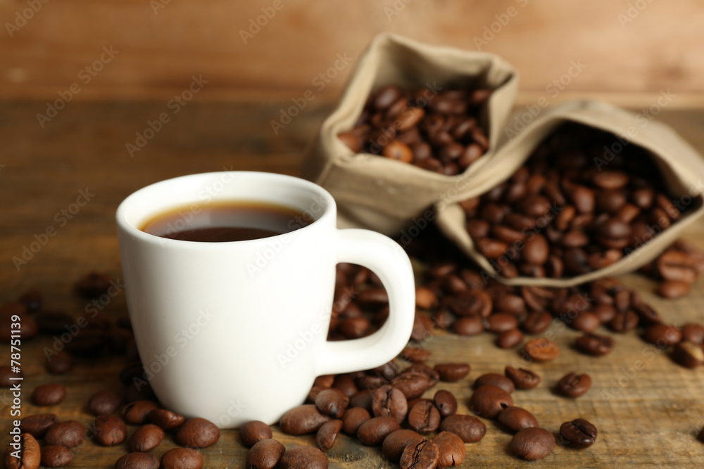 Cup of coffee with beans on rustic wooden background