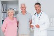 © WavebreakMediaMicro - Happy senior couple with doctor standing in clinic
