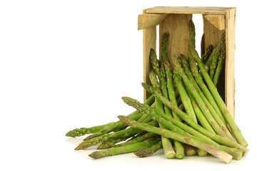  fresh green asparagus shoots in a wooden crate on a white backg