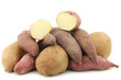 bunch of mixed sweet potatoes and a cut one on a white backgroun