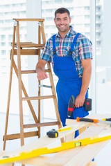 Poster - Carpenter with power drill standing by ladder