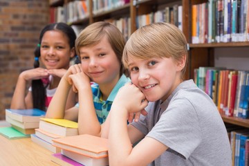 Wall Mural - Cute pupils looking at camera in library