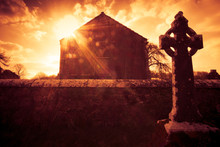 Ireland Celtic Cross At Medieval Cemetery Under Fiery Sky