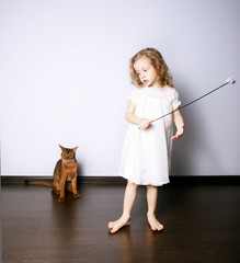 a little girl playing with a cat
