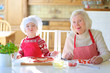 © cromary - Grandmother and granddaughter making pizza together