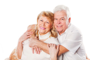 Happy mature senior couple embracing smiling at camera on white