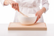 Woman chef mixing something in a white bowl on white background