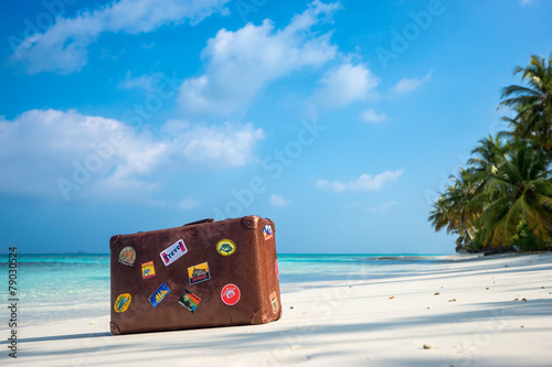 Poster Travel vintage suitcase is alone on a beach