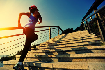 Wall Mural - young fitness woman running on seaside stone stairs