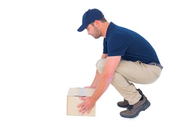 Wall Mural - Delivery man crouching while picking cardboard box