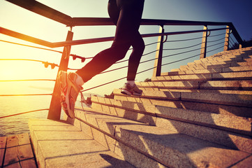 Wall Mural - young fitness woman running on seaside stone stairs